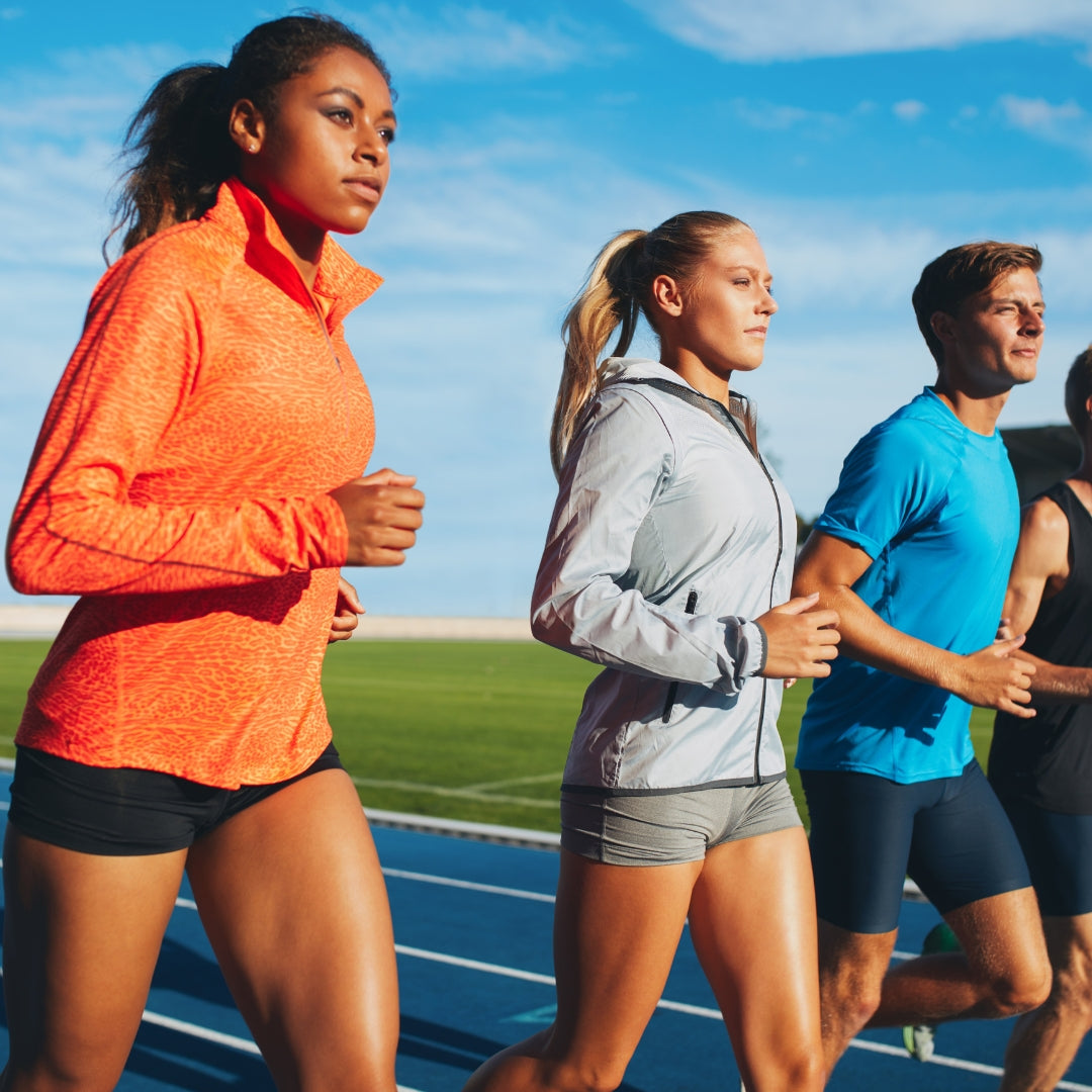 Four runners on a track with a clear blue sky