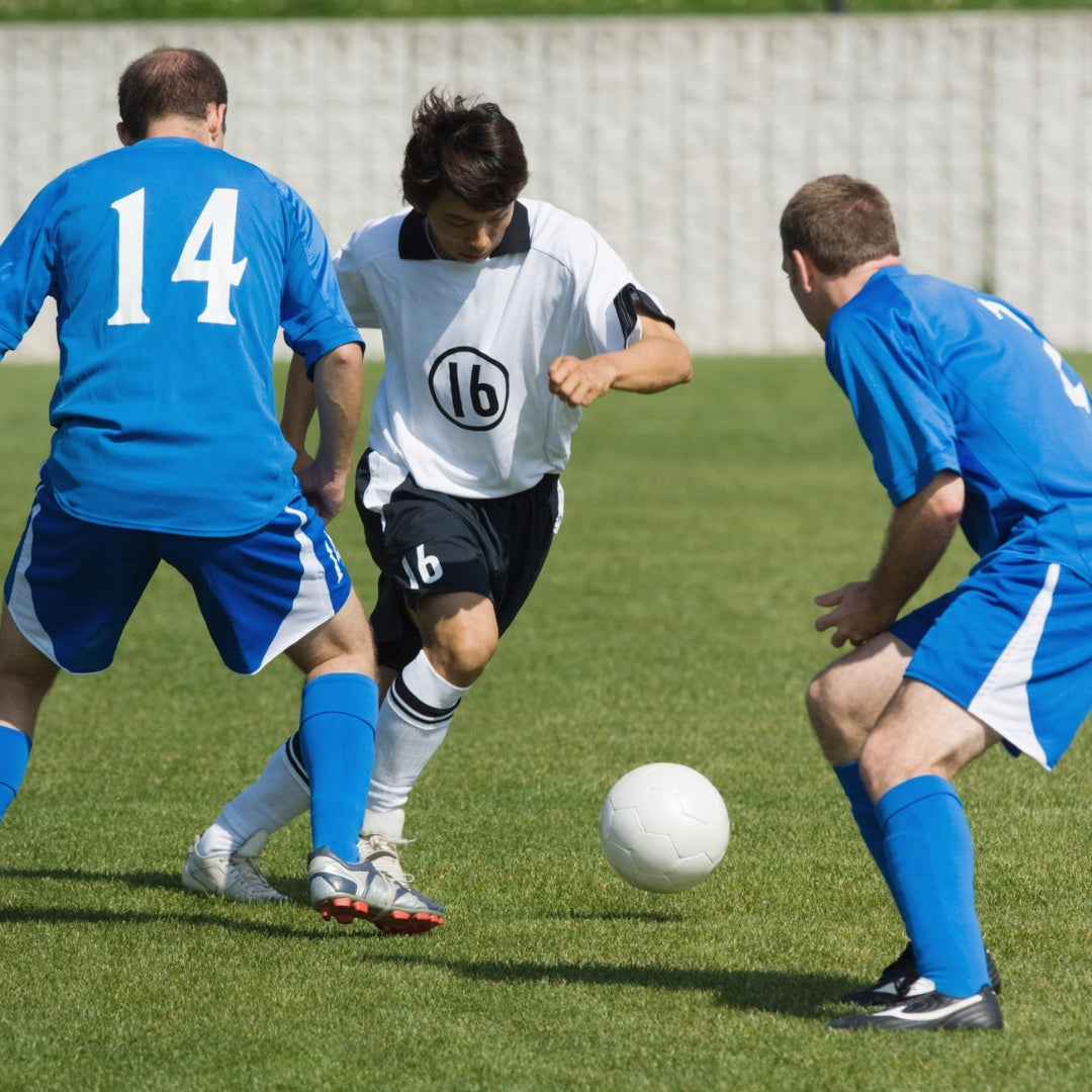 Soccer players in blue and white uniforms playing on a grass field.